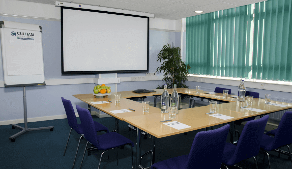 A meeting room with blue chairs and projector screen